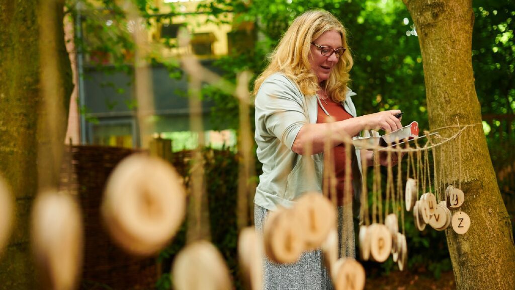 Someone hanging wooden decoration on a rope outside at the forest school